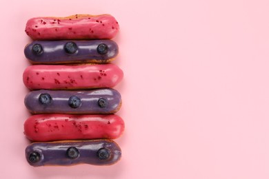 Photo of Delicious eclairs covered with glaze on pink background, top view. Space for text