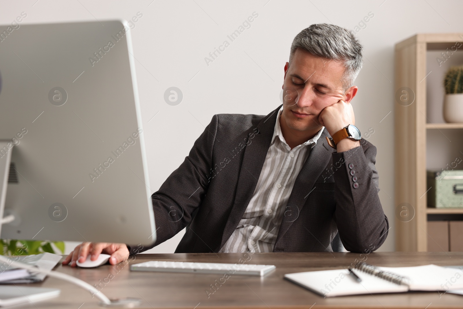 Photo of Man snoozing at wooden table in office