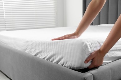 Photo of Woman touching soft mattress indoors, closeup view