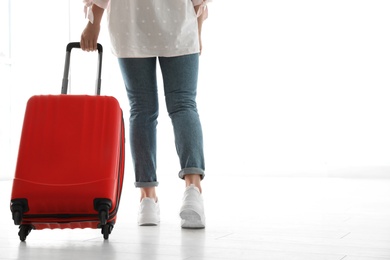 Woman with red travel suitcase in airport. Space for text