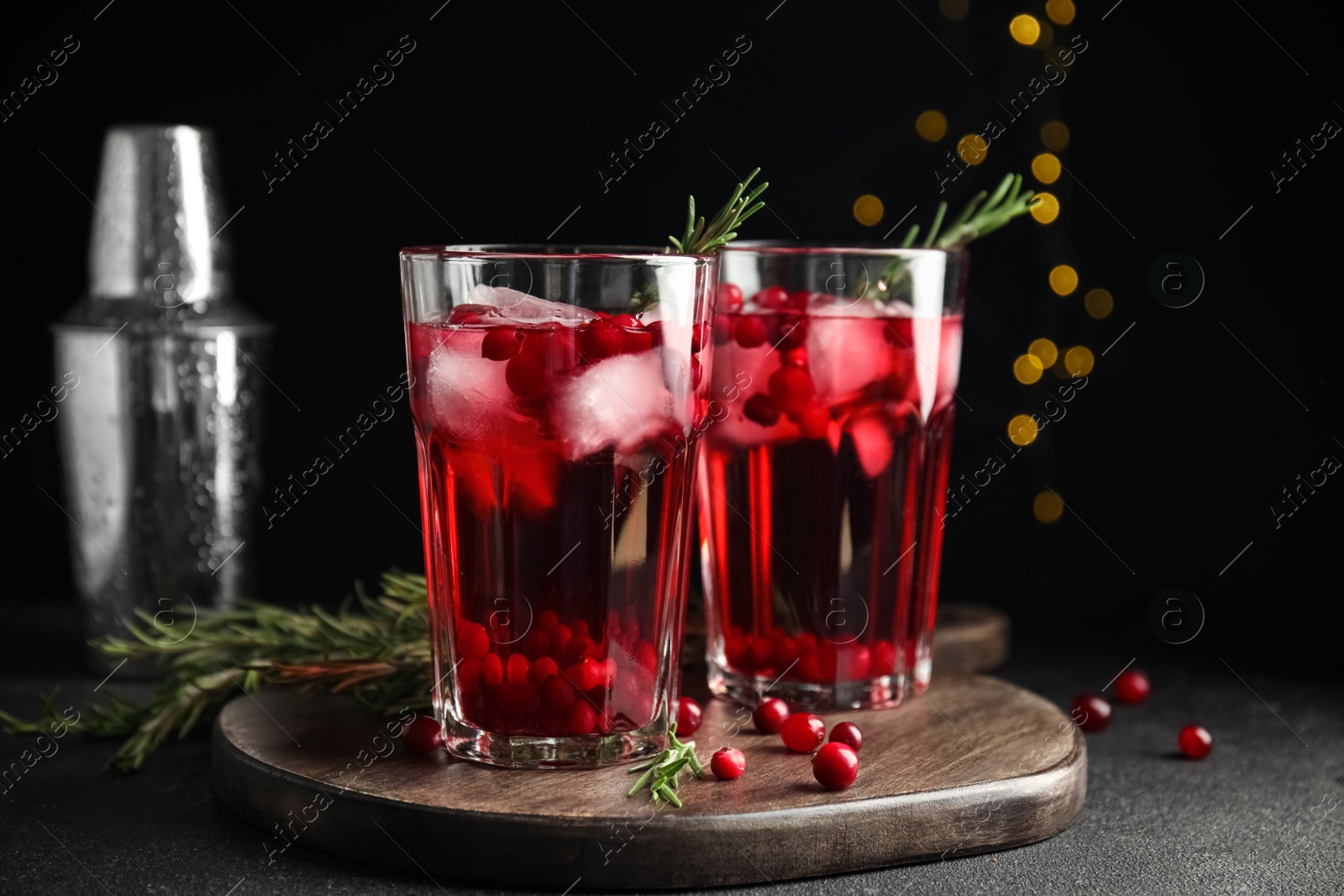 Photo of Tasty refreshing cranberry cocktail with rosemary on black table