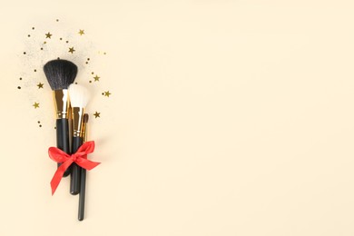 Flat lay composition with makeup brushes on beige background, space for text