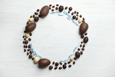 Photo of Frame made of chocolate Easter eggs on wooden background, top view with space for text