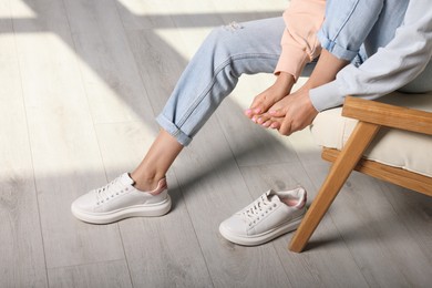 Photo of Woman rubbing sore foot at home, closeup
