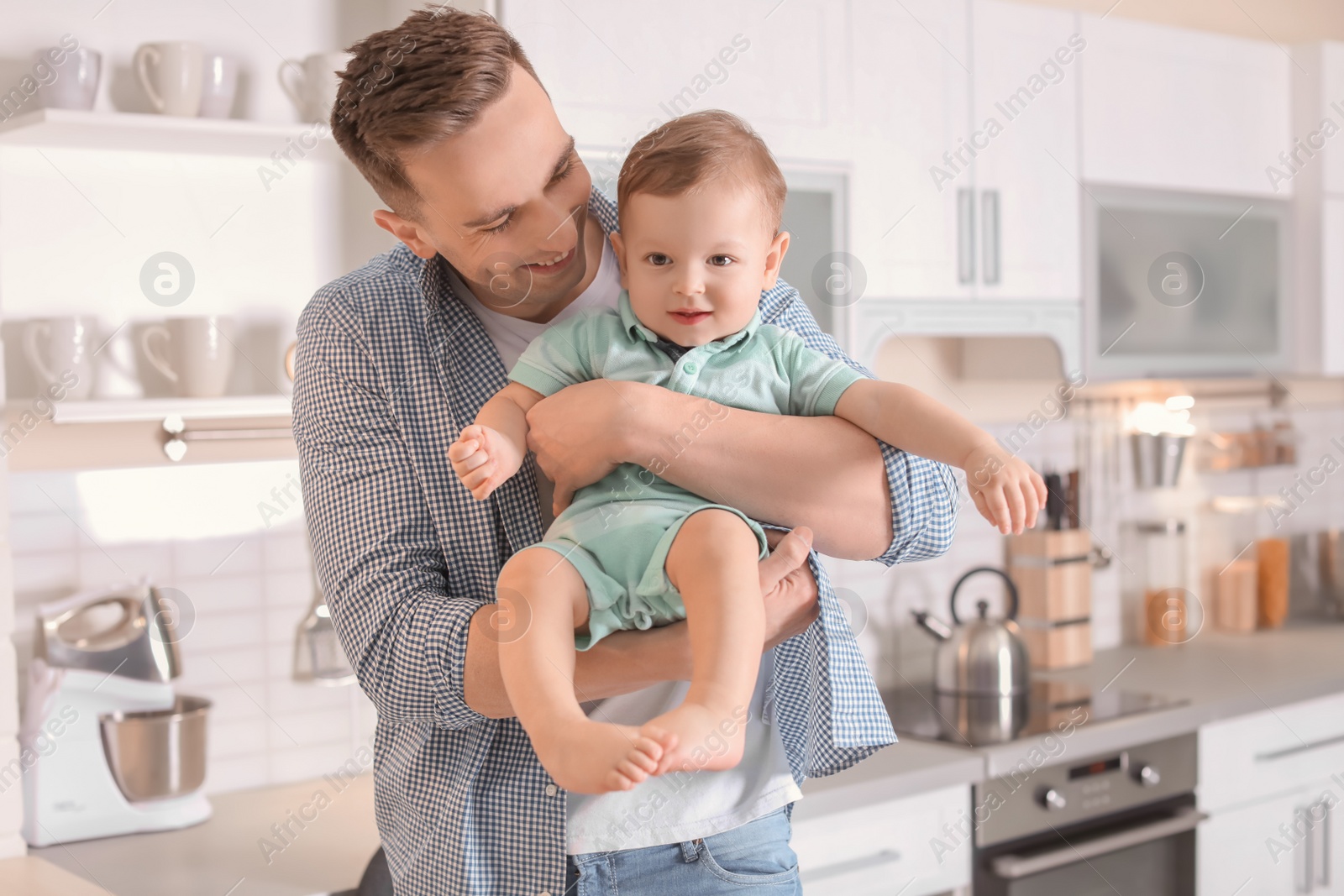 Photo of Young father with his cute little son in kitchen