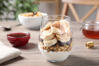 Delicious dessert with banana, granola and yogurt on wooden table