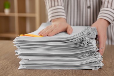 Woman stacking documents at wooden table indoors, closeup