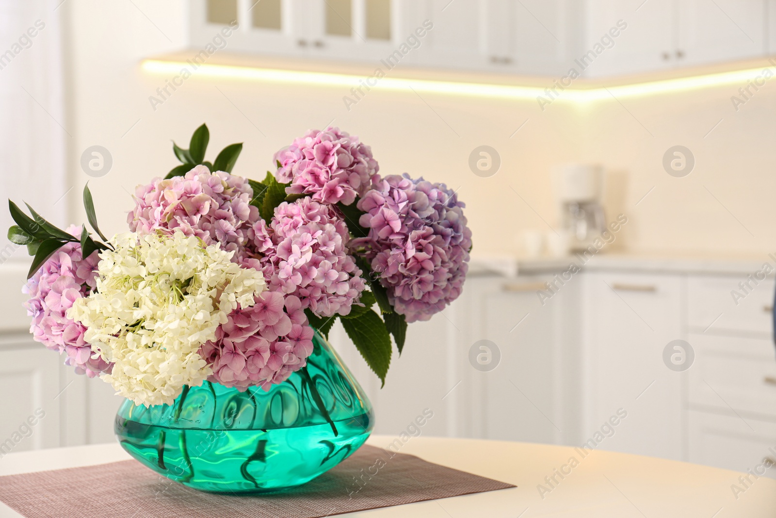 Photo of Bouquet of beautiful hydrangea flowers on table in kitchen, space for text. Interior design