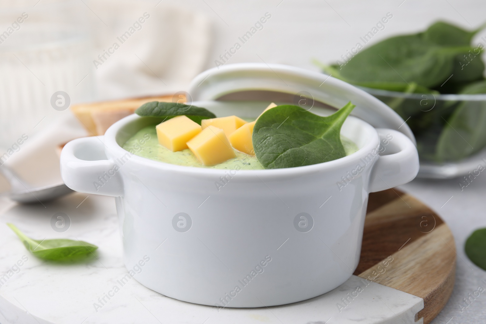 Photo of Delicious spinach cream soup with cheese in bowl on light grey table