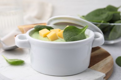 Delicious spinach cream soup with cheese in bowl on light grey table