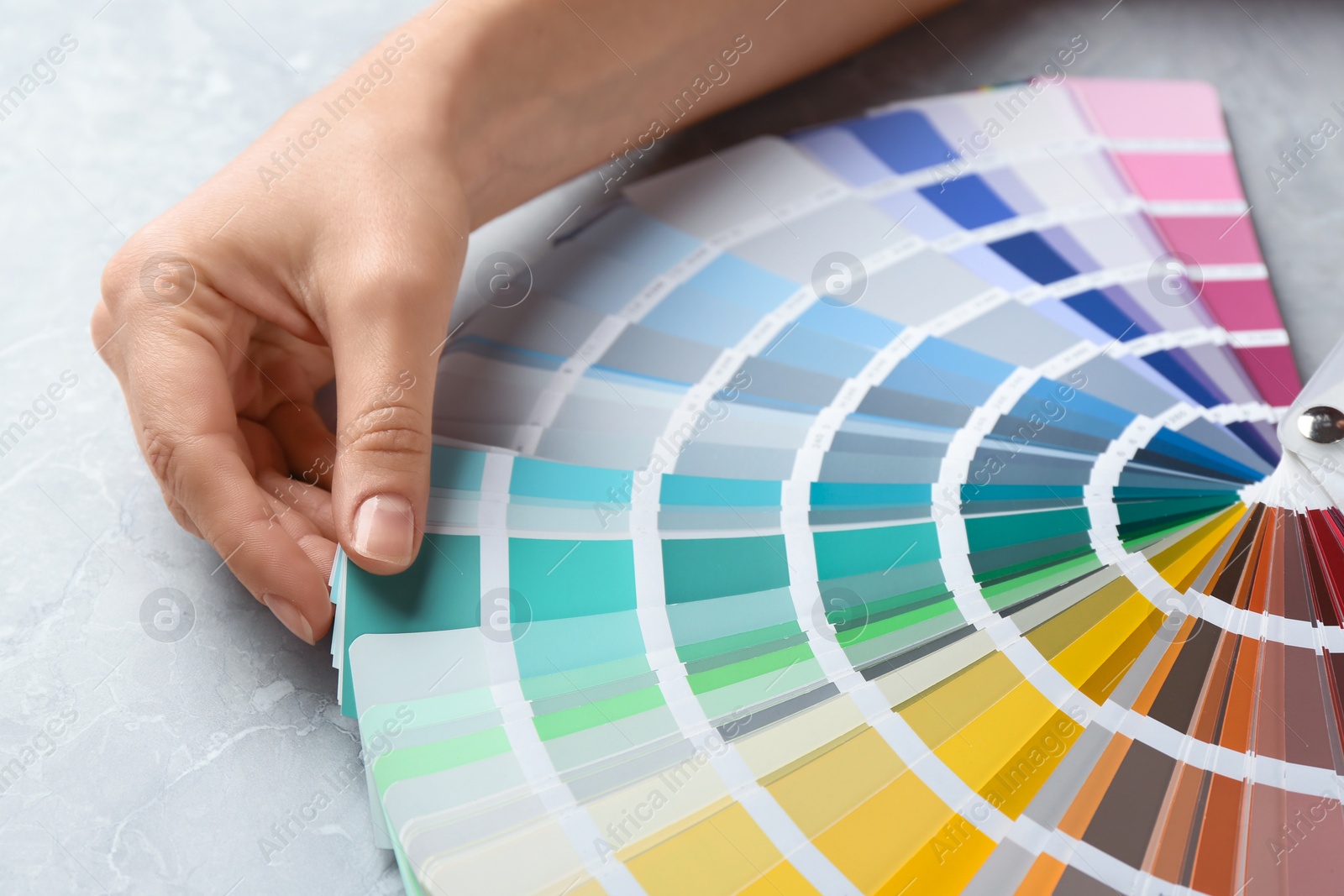 Photo of Woman with palette samples at grey marble table, closeup