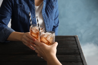 Photo of Friends with glasses of tasty refreshing cola at table, closeup view