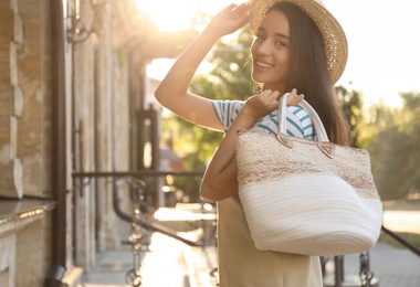 Photo of Young woman with stylish straw bag outdoors