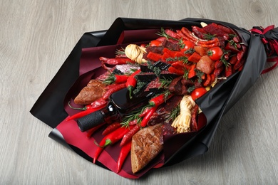 Photo of Beautiful edible bouquet with meat, cheese and vegetables on wooden table, closeup