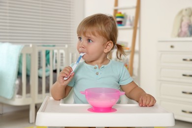 Photo of Cute little child eating tasty yogurt with spoon at home