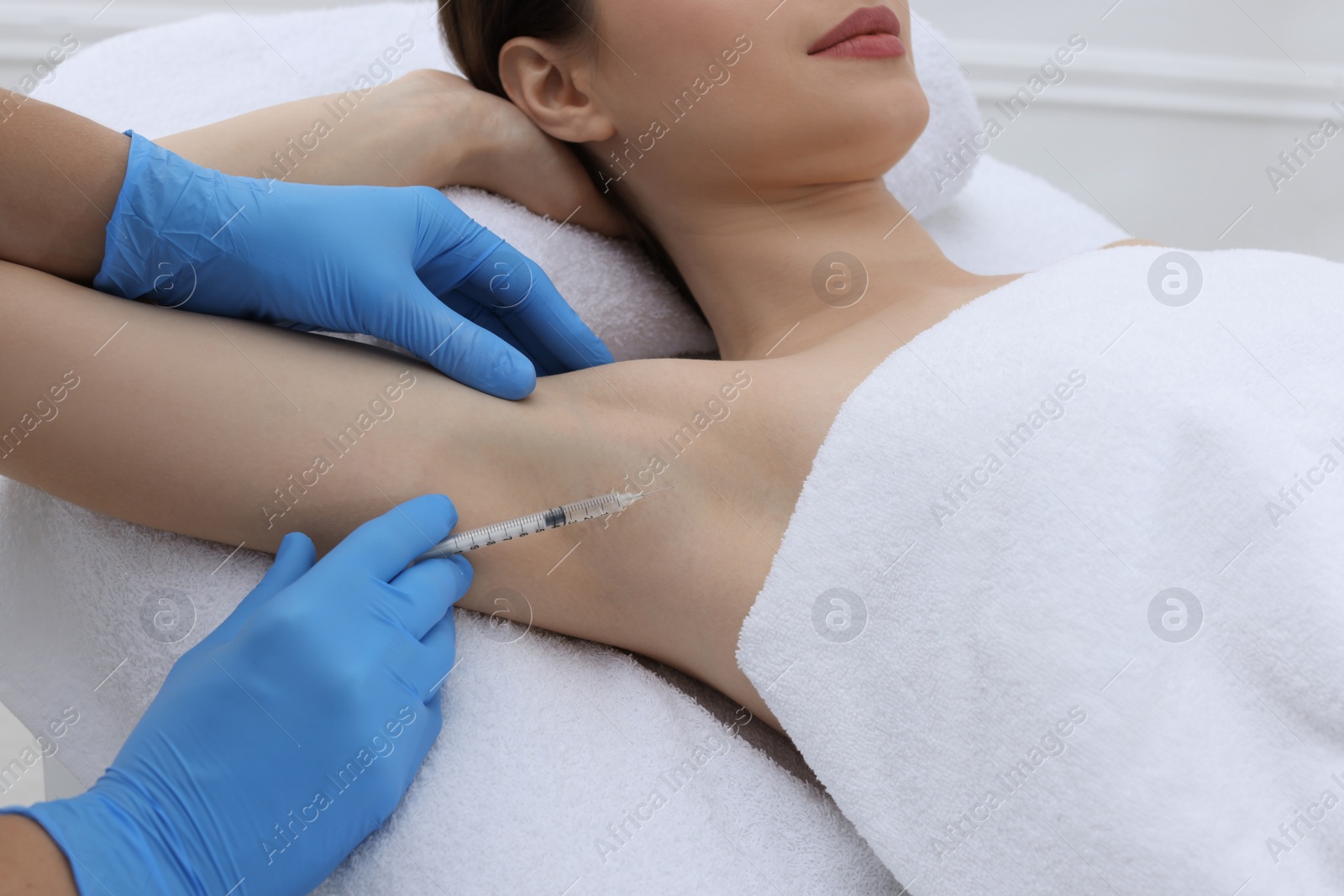 Photo of Cosmetologist injecting young woman's armpit, closeup. Treatment of hyperhidrosis