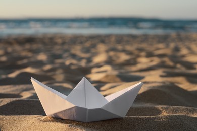 Beautiful white paper boat on sand outdoors, closeup