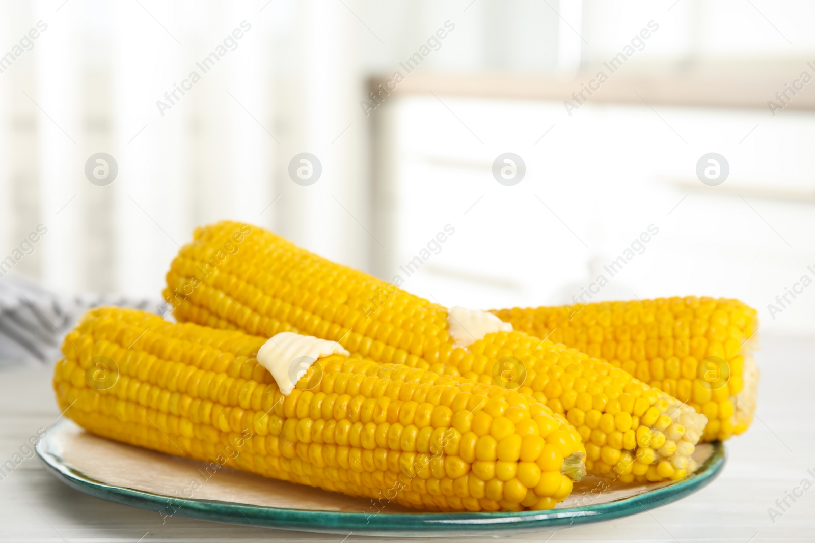 Photo of Fresh corn cobs with butter on white wooden table