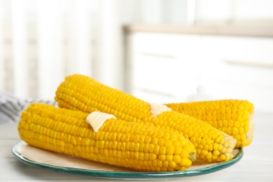 Fresh corn cobs with butter on white wooden table