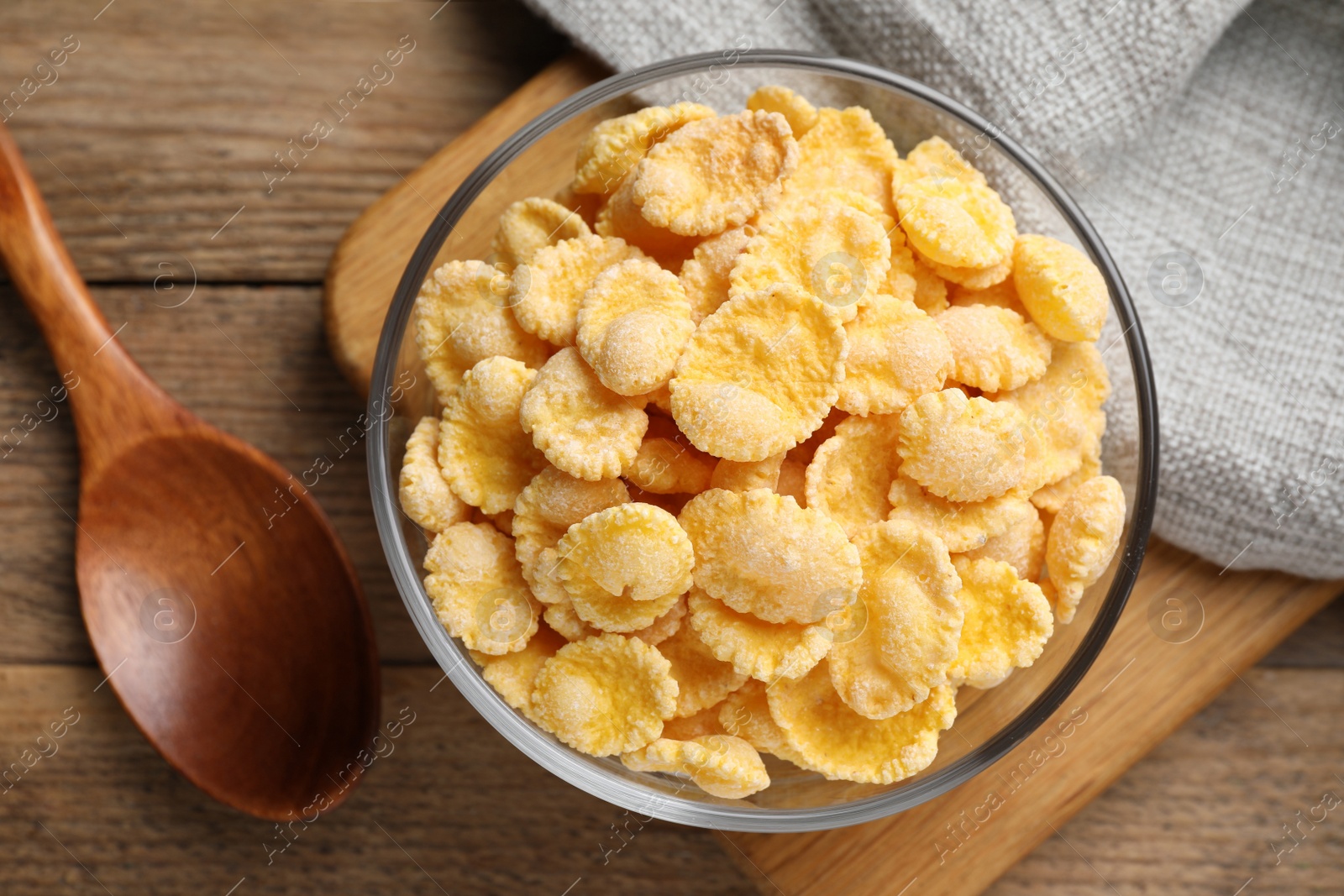 Photo of Bowl of tasty corn flakes on wooden table, flat lay