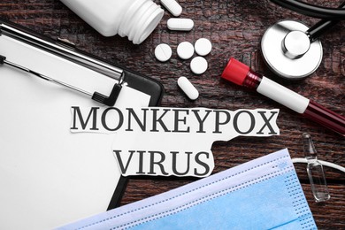 Flat lay composition with words Monkeypox Virus and medical supplies on wooden table