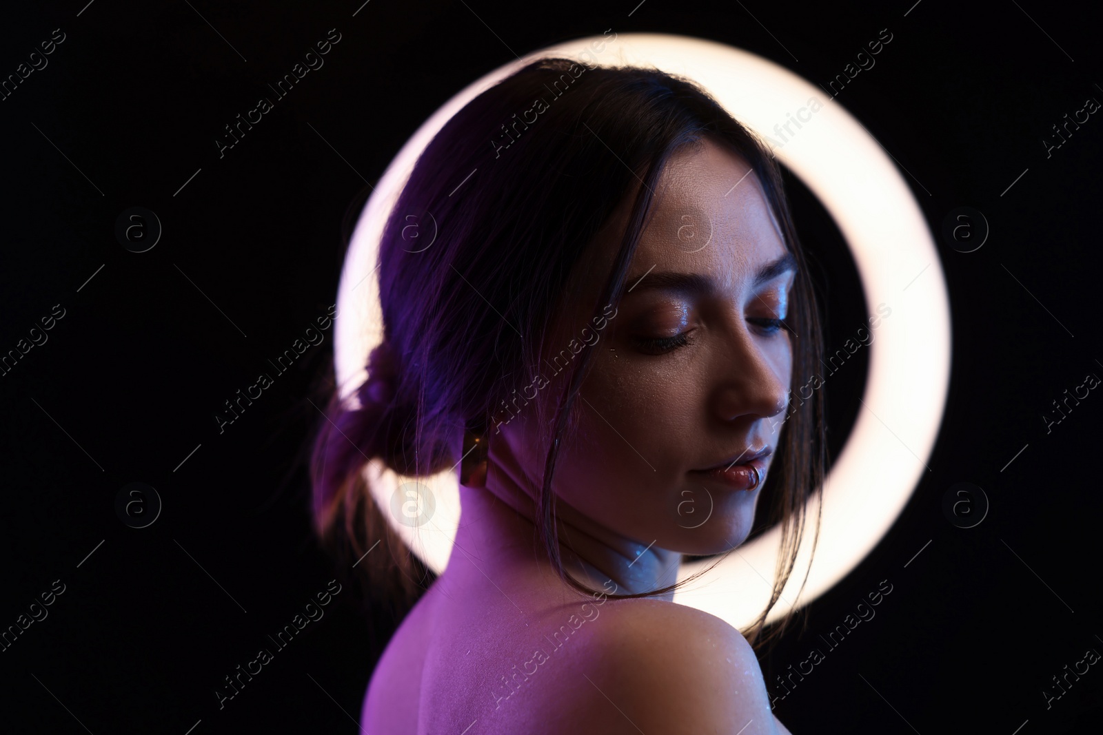 Photo of Beautiful woman and ring lamp on dark background in neon lights