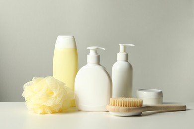 Different bath accessories on white table against grey background