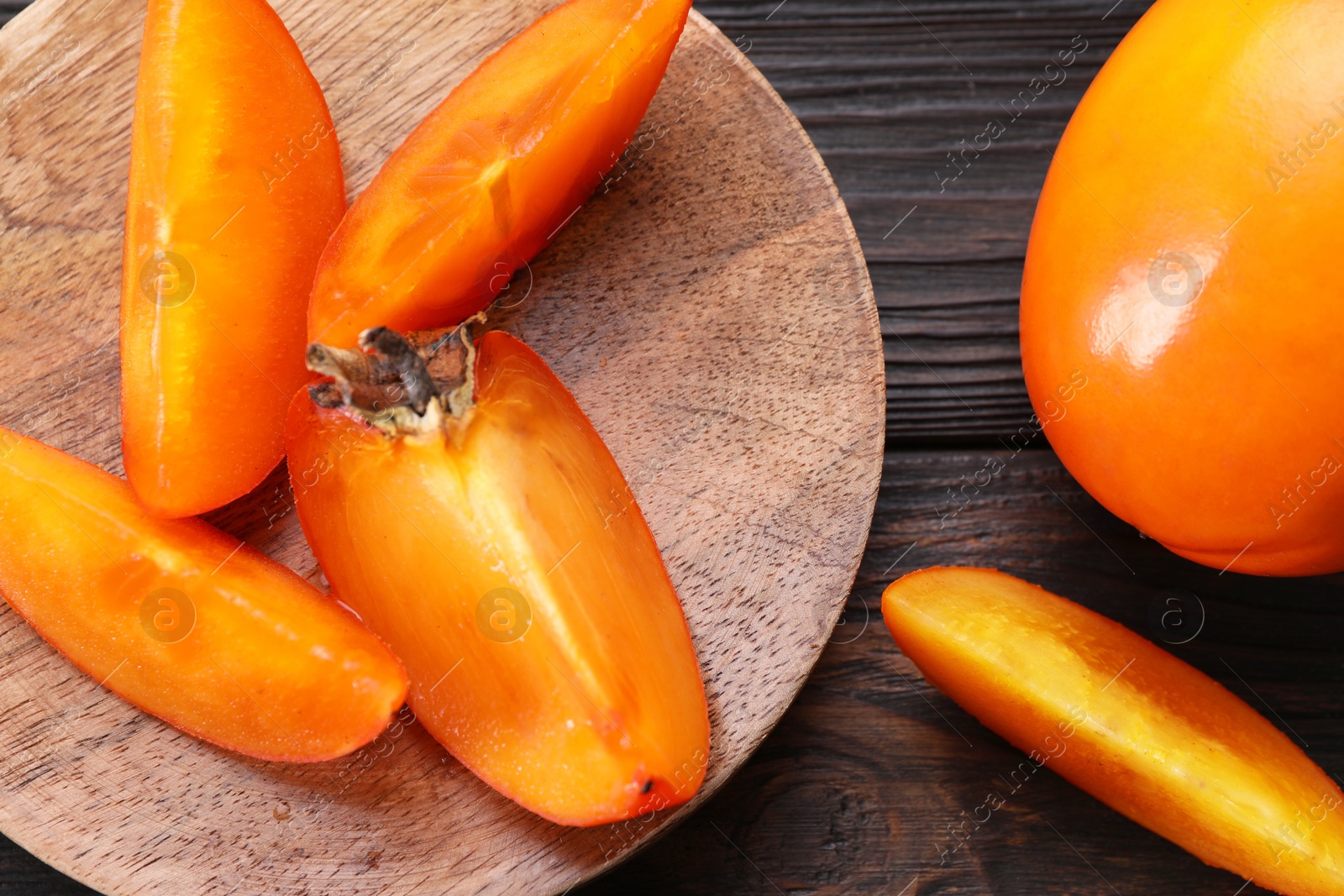 Photo of Delicious ripe persimmons on wooden table, top view