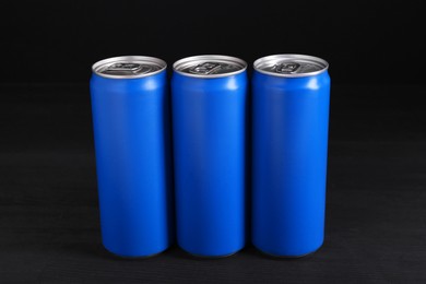 Photo of Energy drinks in blue cans on black wooden table