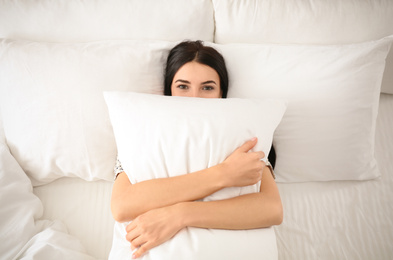 Young woman with pillow in bed, top view. Lazy morning