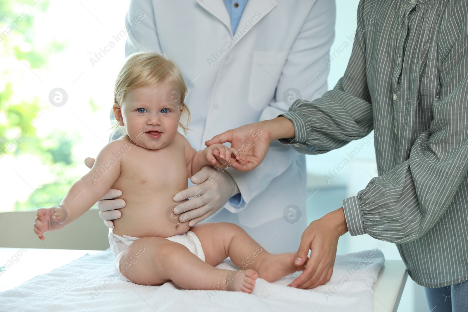 Photo of Mother with her baby visiting pediatrician in hospital. Health growth