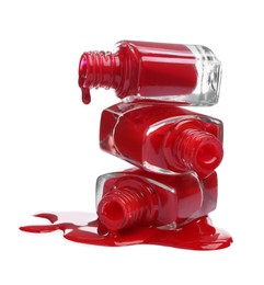 Photo of Red nail polishes dripping from bottles on white background