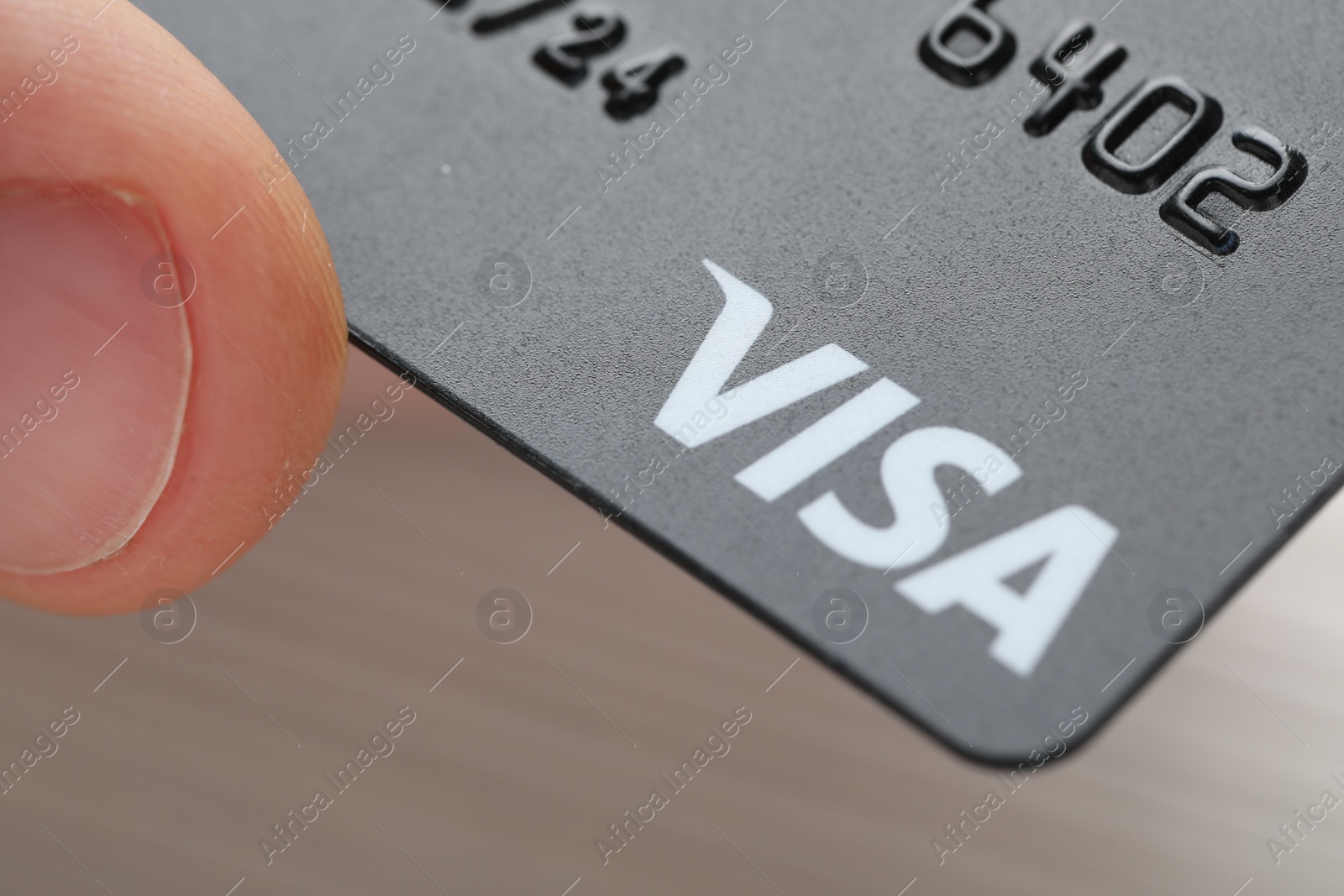 Photo of MYKOLAIV, UKRAINE - FEBRUARY 22, 2022: Woman holding Visa credit card on grey background, closeup