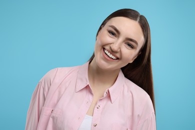 Portrait of beautiful woman laughing on light blue background