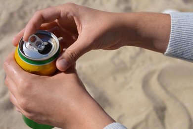 Photo of Woman opening can with sparkling drink at beach, closeup