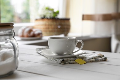 Photo of Tea bag in cup on white wooden table indoors