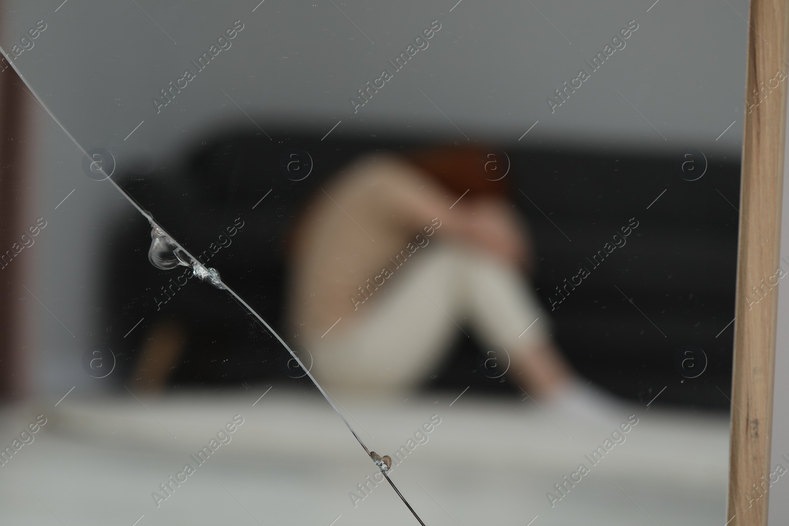 Photo of Mental problems. Blurred reflection of depressed woman in broken mirror