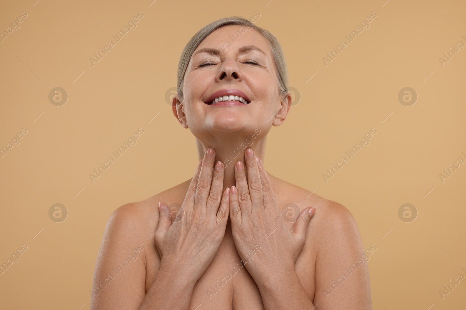 Photo of Beautiful woman touching her neck on beige background