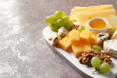 Board with different kinds of delicious cheese and snacks on marble background