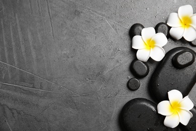 Photo of Zen stones and exotic flowers on grey background, top view with space for text