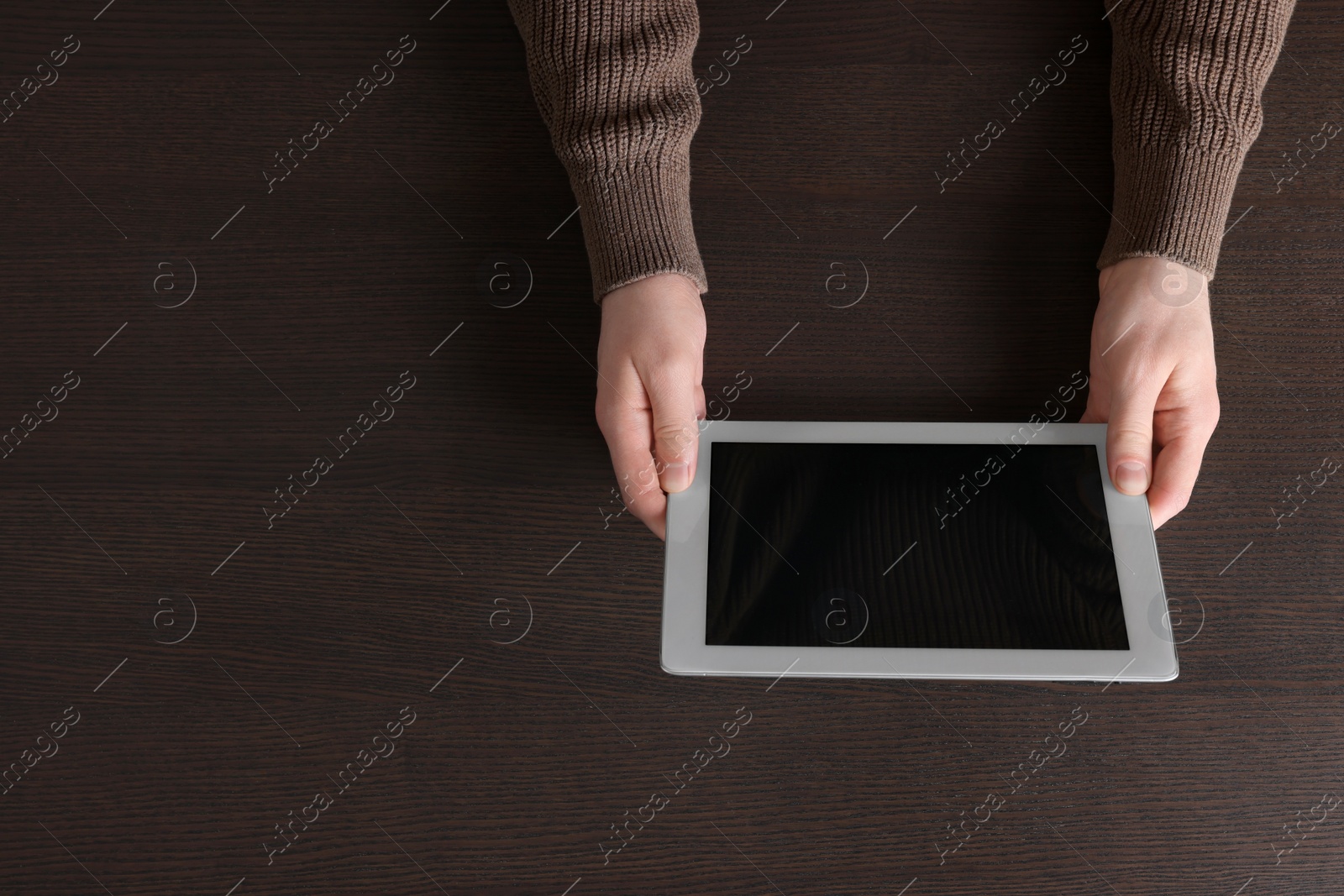 Photo of Man working with tablet at wooden table, top view. Space for text