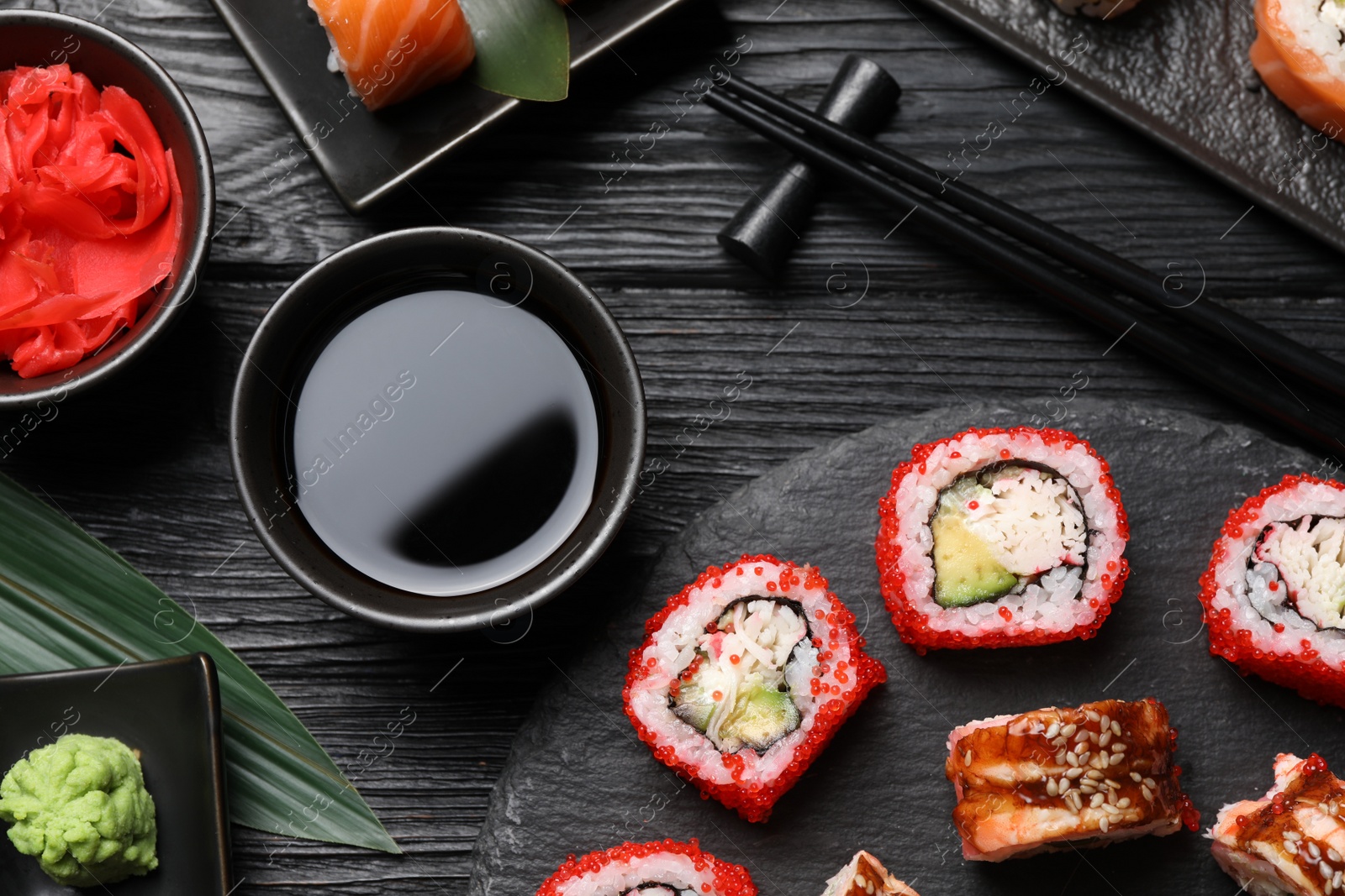 Photo of Flat lay composition with different sushi rolls on black wooden table