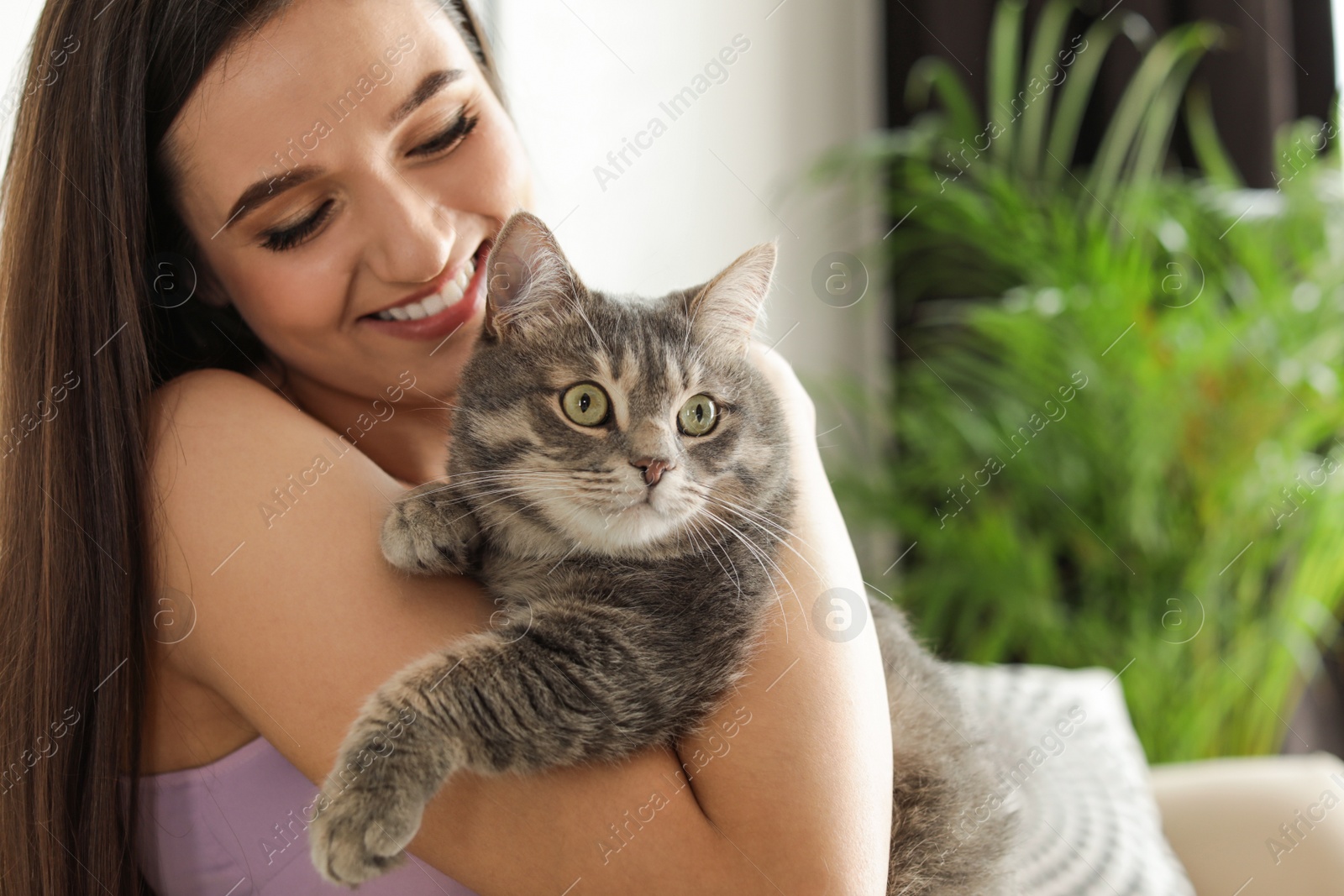 Photo of Young woman with cute cat at home, space for text. Pet and owner