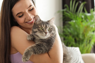 Photo of Young woman with cute cat at home, space for text. Pet and owner