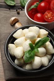 Photo of Delicious mozzarella balls, tomatoes and basil leaves on table, above view
