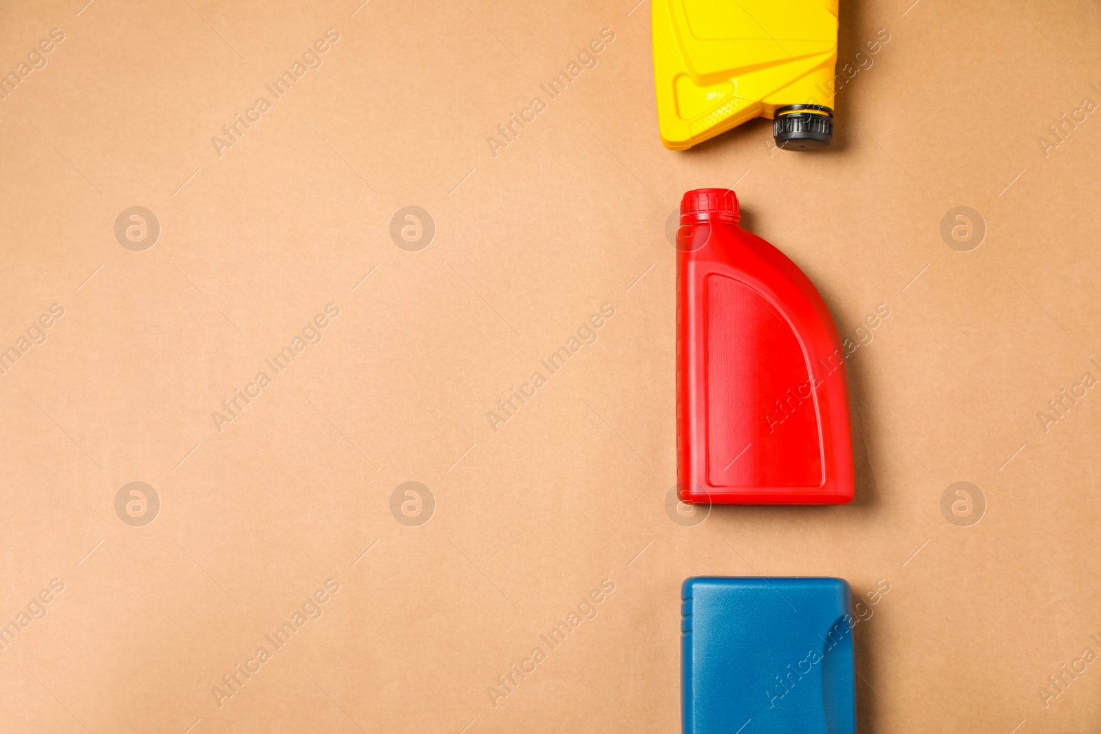 Photo of Motor oil in different canisters on light brown background, flat lay. Space for text