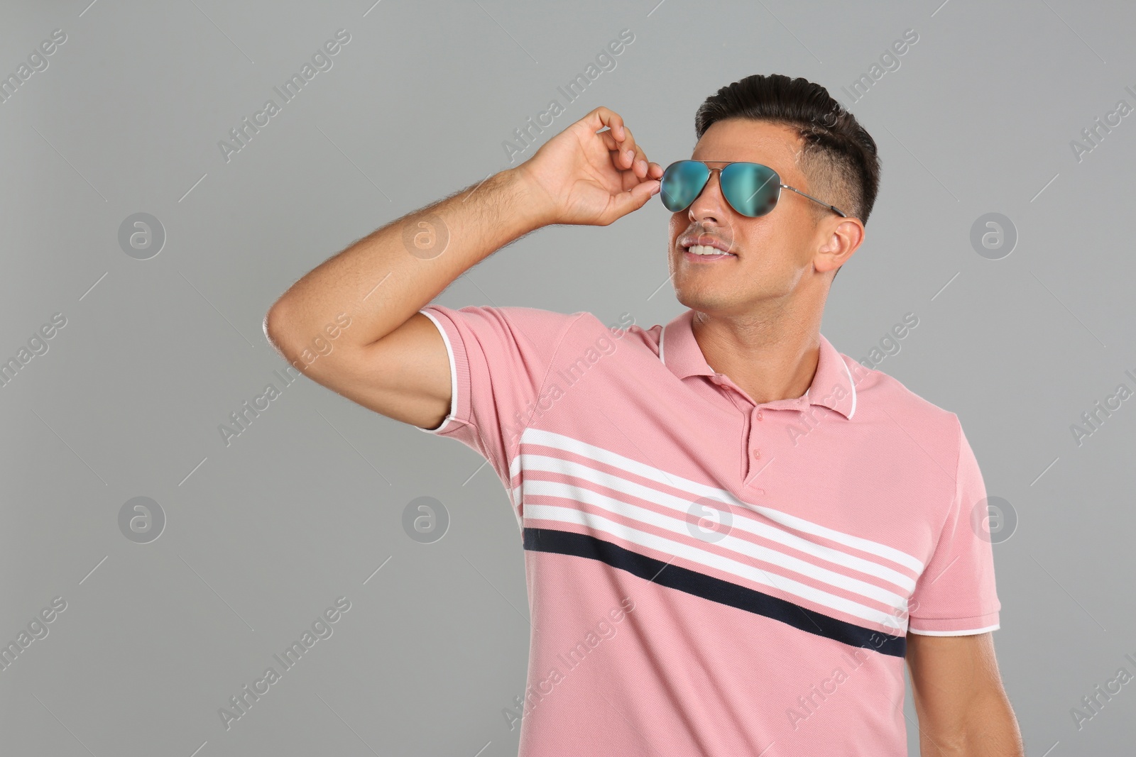 Photo of Handsome man wearing sunglasses on grey background