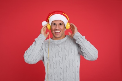 Photo of Happy man with headphones on red background. Christmas music