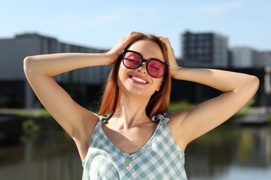 Photo of Beautiful smiling woman in sunglasses near river on sunny day