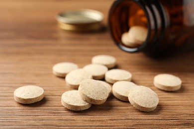 Photo of Dietary supplement pills on wooden table, closeup